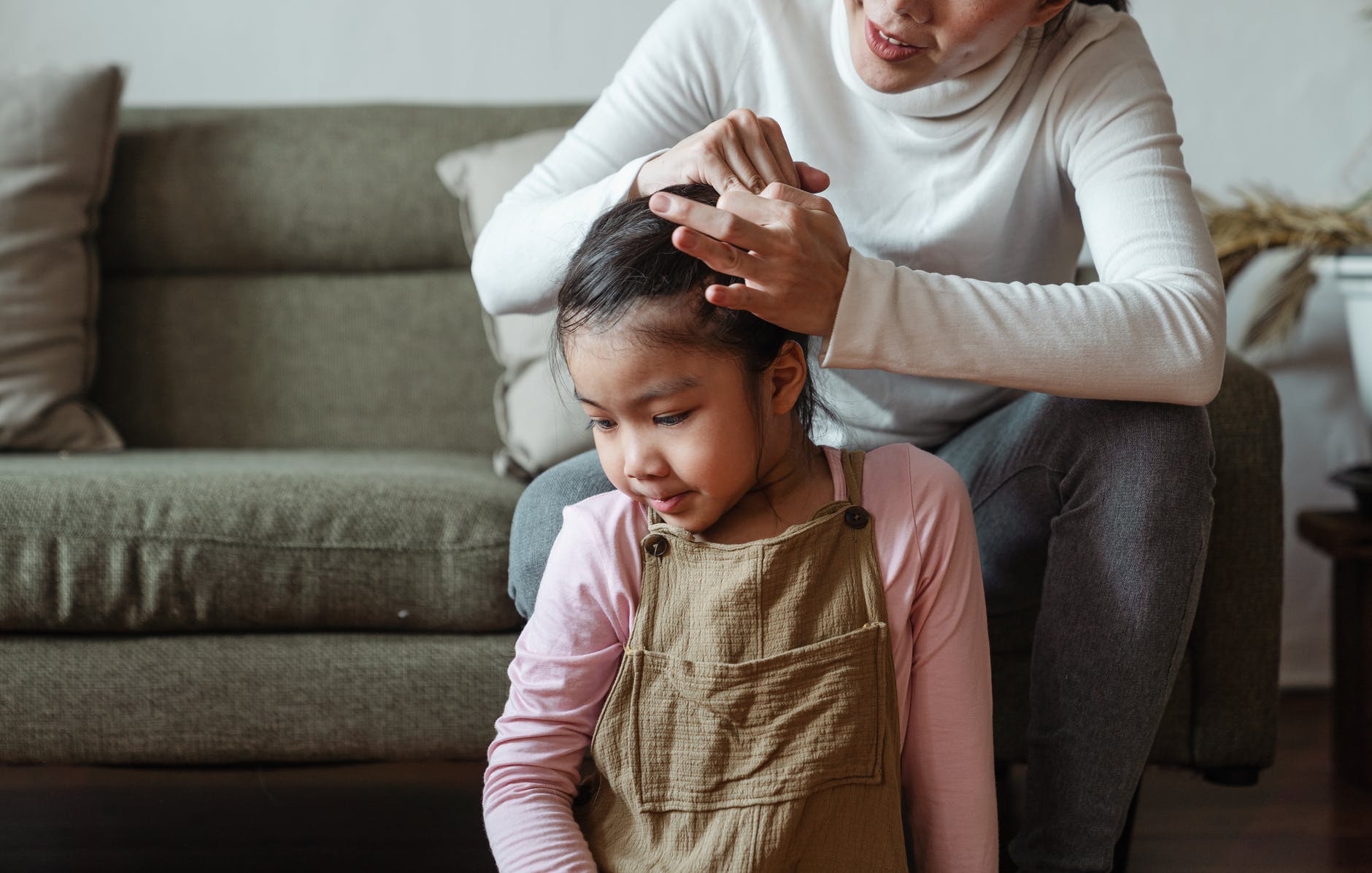photo of woman tying her daughter s hair
