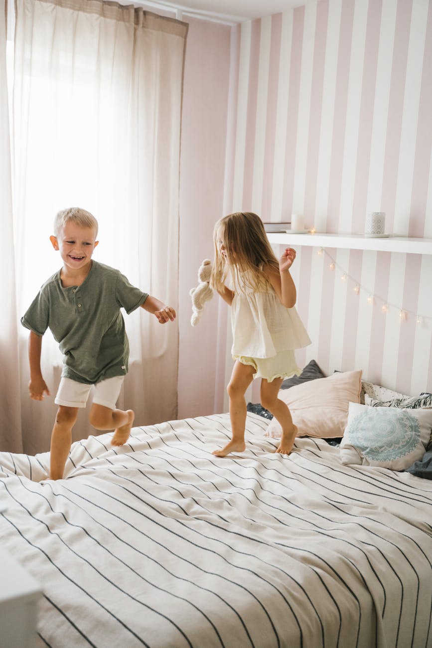 boy and girl standing on white bed