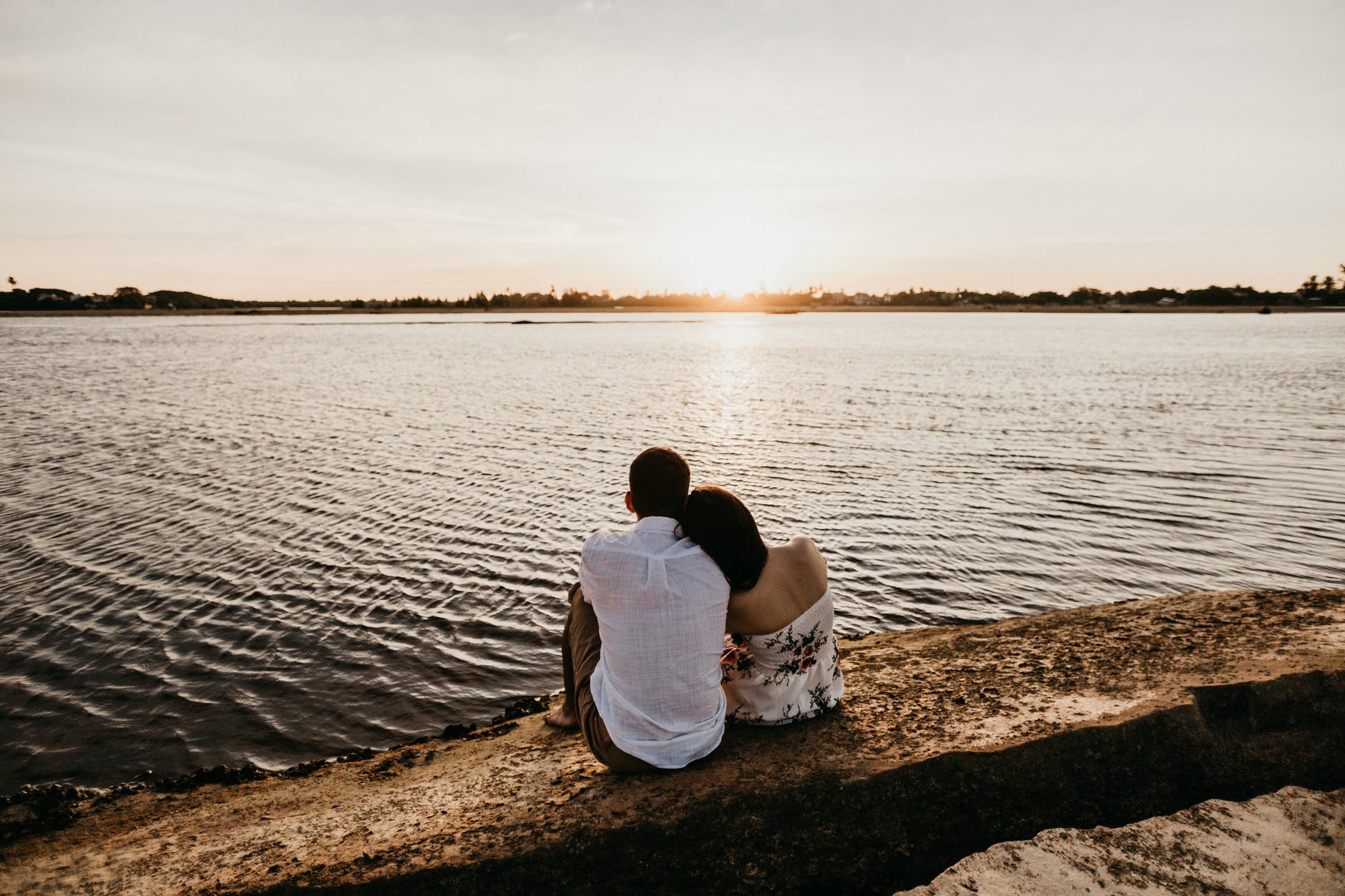 loving couple resting on river coast and enjoying sunset
