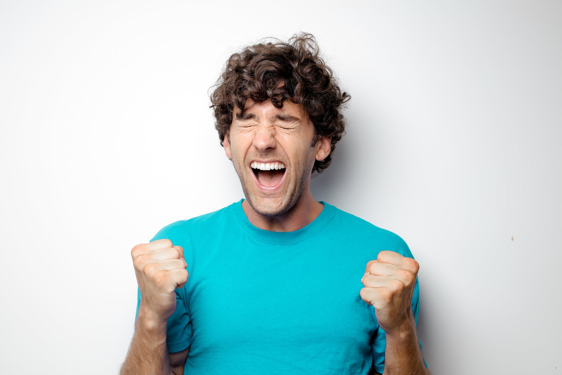 portrait photo of excited man in blue t shirt standing in front of white background